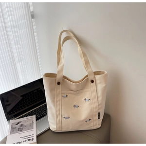 Détail de broderie chiot sur cabas en toile beige avec accent de bouton marron