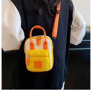 Model view showing the back profile of a tri-color mini crossbody bag with orange strap