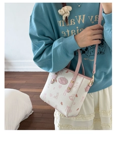 Detail of cartoon bunny print bucket bag with pink handles and gold hardware on a model