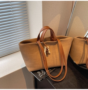 Detail of vintage canvas tote with leather trim and wooden bead tassel in soft lighting