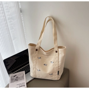 Gros plan sur le sac fourre-tout en toile blanc cassé avec broderie de teckel et bouton