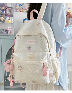 Detail showing white quilted backpack with star embroidery and pink heart charm