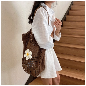 Détail d'un sac cabas en crochet marron foncé orné d'une grande fleur blanche déco