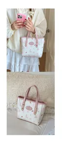 Detail of cream white bucket bag with pink rabbit print and gold rivet hardware accents