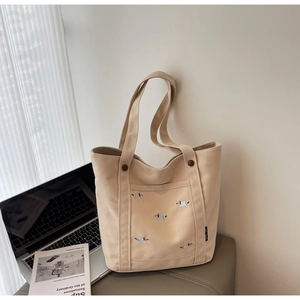 Gros plan détaillé du sac cabas en toile beige avec broderie de chiots bleus et blancs