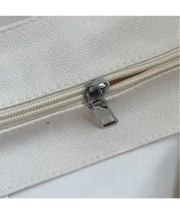Macro view of high-density nylon zipper with a polished silver metal puller on canvas bag