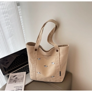Détail du sac cabas en toile beige avec broderie de chien colorée et poche externe