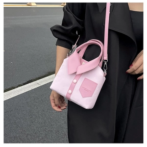 Detail of pink shirt-shaped handbag with collar and buttons on asphalt street