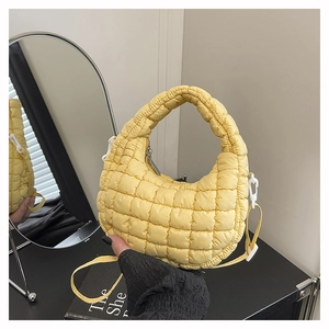 Detail of bright yellow quilted dumpling bag featuring puffy texture and metallic zipper