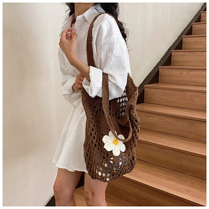 Texture détaillée d'un sac cabas au crochet marron avec une fleur de marguerite blanche
