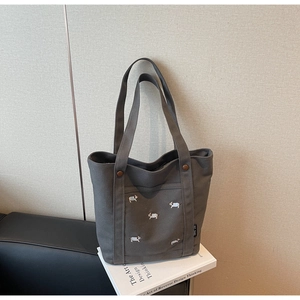 Vue détaillée du sac cabas en toile grise avec chiots brodés et étiquette de marque