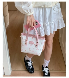 Close-up of a small tote bag with pink rabbit prints and dual handles on a white base