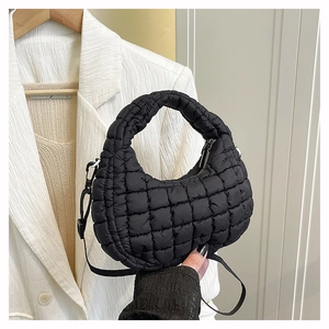 Detail view of black quilted dumpling bag with adjustable strap and metallic hardware