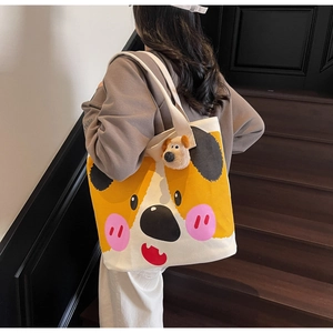 Nahaufnahme der weißen Canvas-Tragetasche mit gelbem Corgi-Print und Plüsch-Hundeanhänger