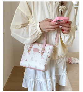 Detail shot of white bucket bag with pink rabbit pattern and metal feet at the bottom