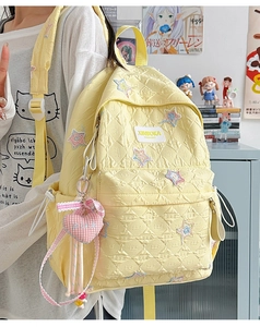Detail of yellow quilted star backpack with heart charm in a lifestyle setting