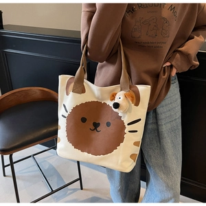 Detail der cremeweißen Canvas-Tasche mit braunem Hundedruck und Plüsch-Anhänger