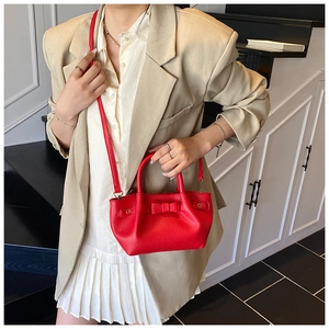 Borsa a secchiello rossa in pelle con fiocco indossata da modella in completo beige