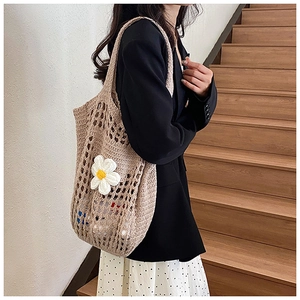 Détail d'un sac cabas en maille tricotée main avec une fleur de marguerite blanche
