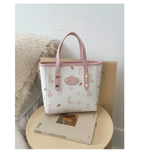 Close-up of a white mini bucket bag with pink rabbit patterns on a wooden stool