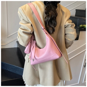 Back view of model wearing pink pebbled leather baguette bag with tassel detail