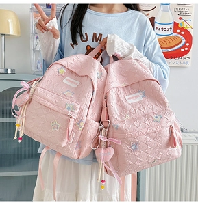 Detailed view of pink quilted star backpack with cute heart charms and ribbon details