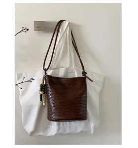 Detailed view of dark brown woven bucket bag with decorative wooden beads and shoulder strap