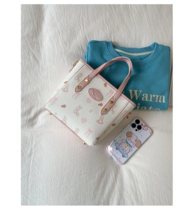 Detailed close-up of a white tote bag with pink bunny prints and gold metal rivets