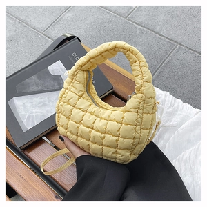 Close-up of quilted pale yellow cloud bag with soft padded texture and carry handle