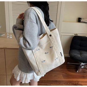 Détail du sac cabas en toile crème avec broderie de chiot et étiquette de marque