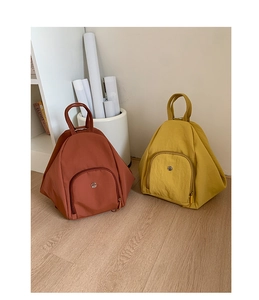 Detail view of stylish triangular nylon backpacks in red-brown and bright yellow colors