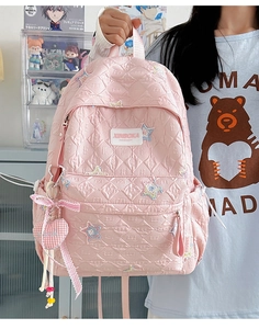 Detail of pink quilted backpack with sequin star patches and a heart charm