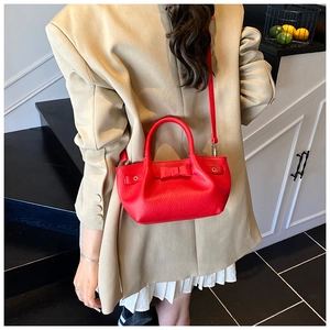 Vista posteriore di una borsa a secchiello in pelle rossa con fiocco su blazer beige