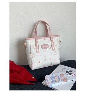 Detail of printed white tote bag with pink bunny patterns and gold metal hardware