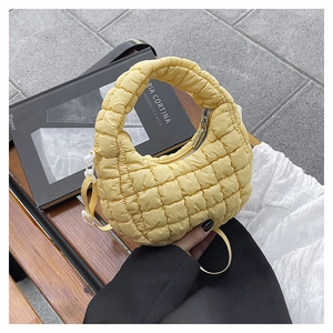 Close-up of yellow quilted crescent dumpling bag with zipper and adjustable strap