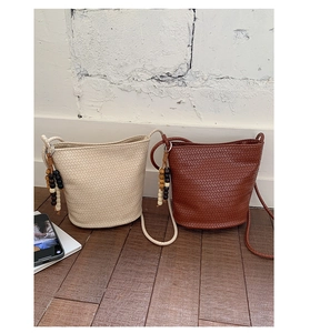 Detail of woven texture on cream and brown bucket bags with wood bead tassels