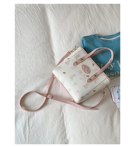 Detailed overhead shot of a mini bucket bag with pink cartoon rabbit patterns on white leather