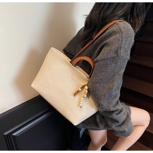 Minimalist cream canvas tote bag with brown leather straps and beaded tassel detail