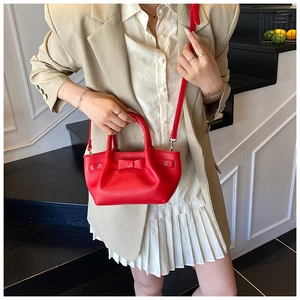 Dettaglio della piccola borsa a secchiello rossa in pelle con fiocco decorativo