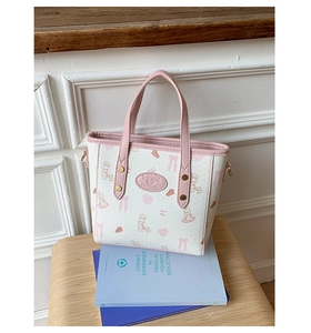 Detail of pink and white bucket bag with rabbit and bow prints on wooden stool