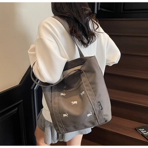 Gros plan d'un sac cabas en toile gris foncé avec des broderies de chiens et un logo