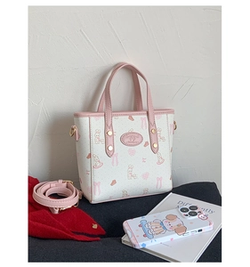Detailed macro view of the cute white bucket bag featuring pink rabbit prints and golden hardware