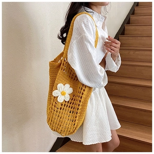 Gros plan d'un sac cabas en crochet jaune avec marguerite blanche porté par un mannequin