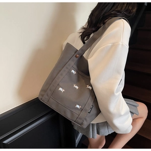 Détail du sac cabas en toile grise avec broderies de chiens et large bandoulière