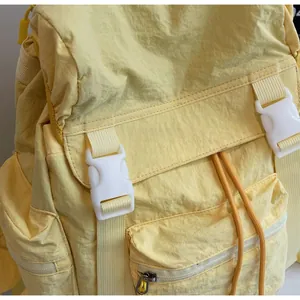 Vue détaillée des boucles blanches et du cordon sur le sac à dos en toile jaune