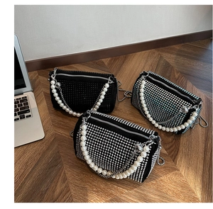 Detailed view of mini Boston bags with rhinestones and pearl handle on wooden floor