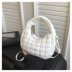Detail shot of white quilted puffy handbag with top zipper and textured fabric surface