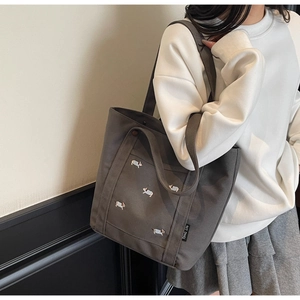 Détail du sac cabas en toile gris foncé avec broderie corgi et étiquette de marque latérale
