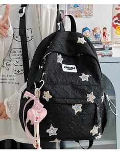 Detail of black quilted star backpack with sequin stars and a pink heart pendant