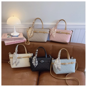 Détail de sacs seaux colorés en similicuir avec texture gaufrée et poignées foulard en soie